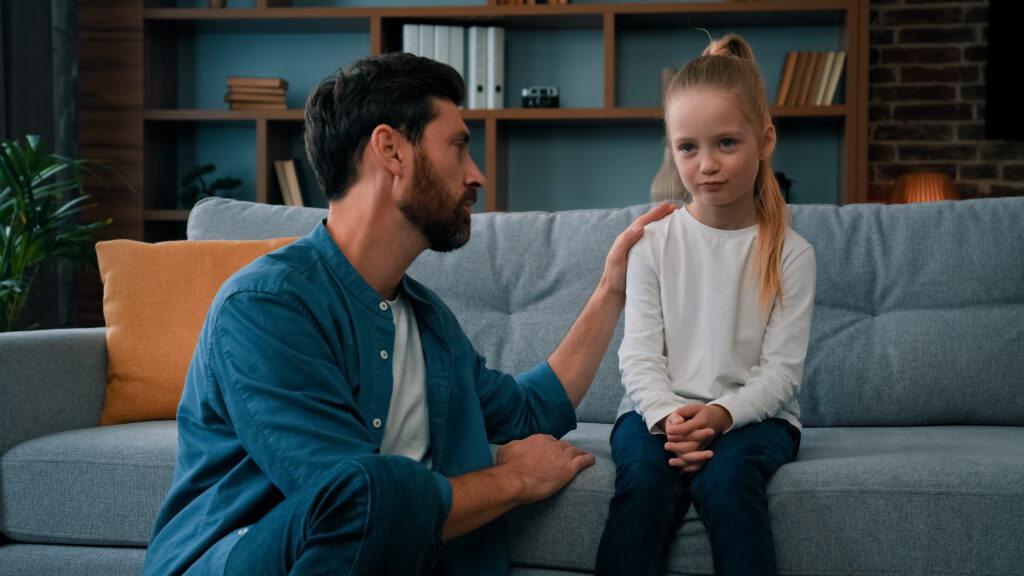 Padre consolando a su hija en el sofá